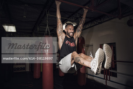 Male boxer training on bar with gritted teeth in gym