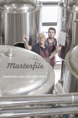 Brewers in brewery next to stainless steel tanks