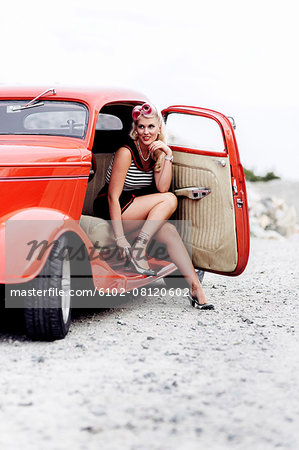 Woman wearing retro clothes sitting in vintage car