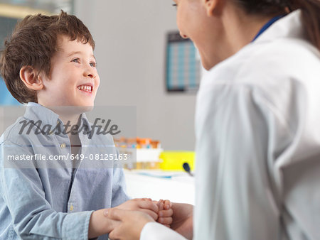Doctor comforting young boy in clinic