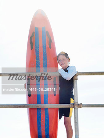 Portrait of boy nipper (child surf life savers) leaning against railings, Altona, Melbourne, Australia