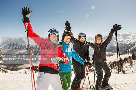 Portrait of skiers on slope, arms raised, smiling