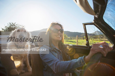 Mature woman and dog, in convertible car