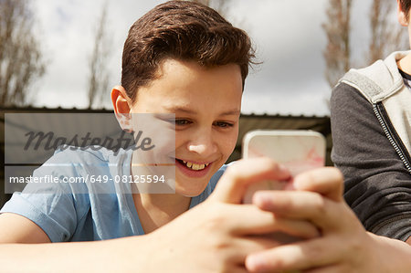 Smiling boy reading smartphone text message