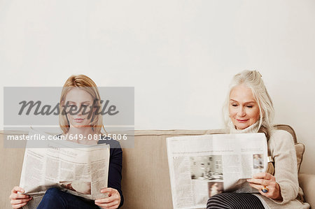 Senior and mid adult women reading newspapers