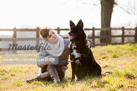 Mid adult woman sitting with her dog in field