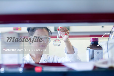 Young female scientist holding up volumetric flask in lab Young female scientist holding up volumetric flask in lab
