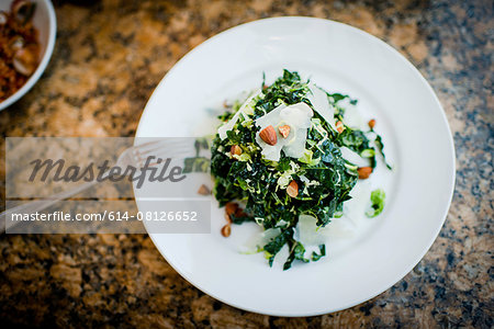 Plate of kale salad and nuts on restaurant table