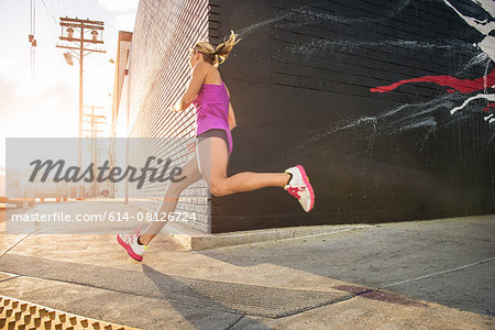 Female runner running along sidewalk Female runner running along sidewalk