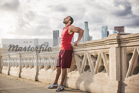 Male runner leaning back taking a break on bridge, Los Angeles, California, USA
