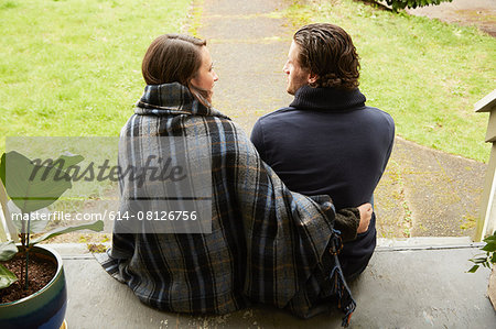Rear view of young couple sitting on porch step