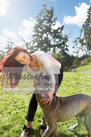 Young woman petting her dog in park