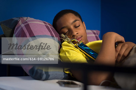 Teenage boy asleep in bunkbed hugging trophy