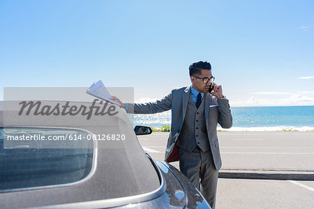 Young businessman at coastal parking lot talking on smartphone