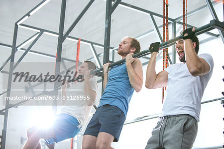 Low angle view of dedicated men doing chin-ups in crossfit gym