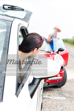 Woman looking at female crashing car on road