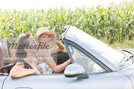 Happy friends enjoying road trip in convertible