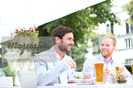 Happy businessmen having food at sidewalk cafe