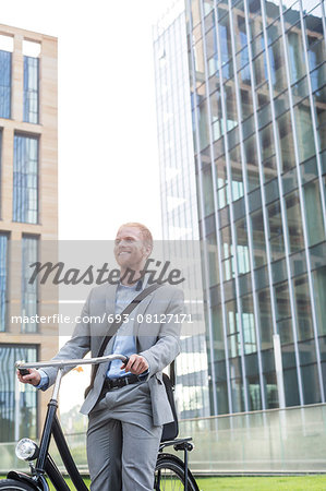 Happy businessman with bicycle standing outside office building