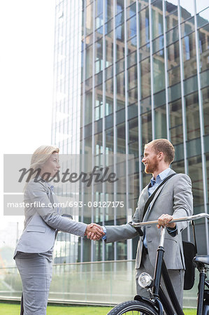 Businesspeople shaking hands outside office building