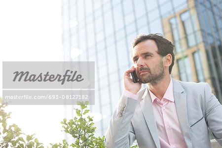 Businessman answering mobile phone outside office building