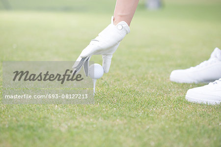 Cropped image of woman placing ball on golf tee