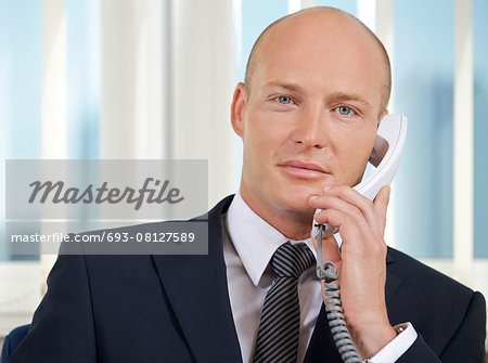 Portrait of businessman talking on telephone at office