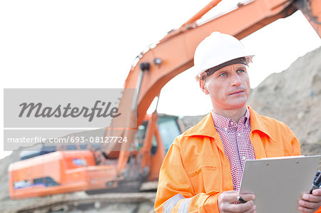 Supervisor looking away while holding clipboard at construction site