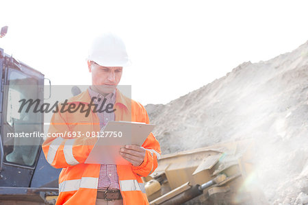 Engineer reading clipboard at construction site