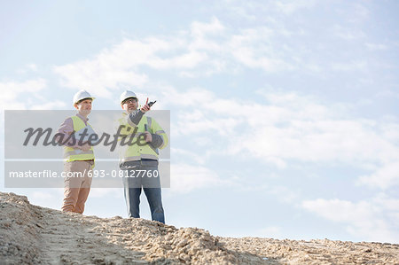 Low angle view of supervisors discussing at construction site against sky