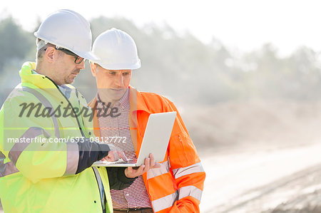 Supervisors using laptop at construction site Supervisors using laptop at construction site