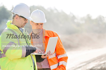 Supervisors using laptop at construction site