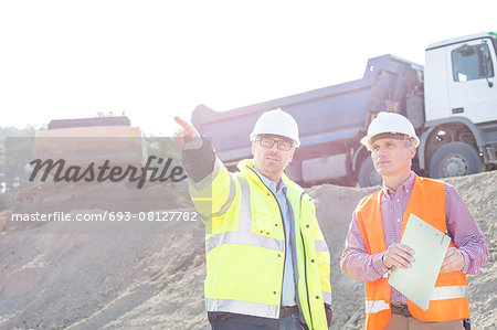 Supervisor showing something to colleague while discussing at construction site