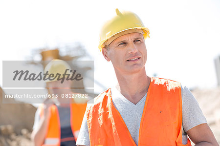 Male worker at construction site with colleague standing in background