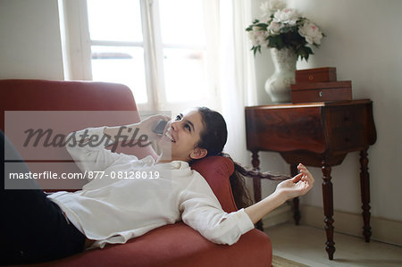 A teenage girl phoning, lying on a sofa