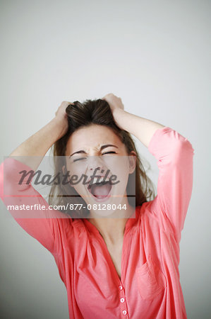 Portrait of a teenage girl tearing her hair out and screaming