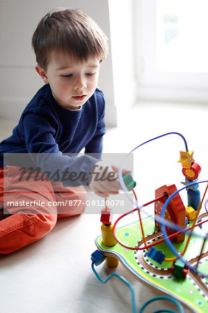 Little boy playing with wood toy cars