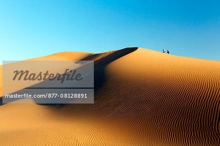 Morocco. Draa Valley. Tinfou. Tinfou dunes. Sunrise over the dunes. Tourists climbing the dune.
