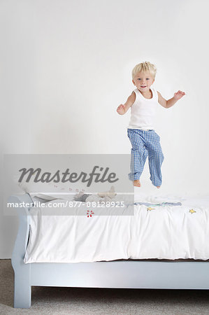 Little boy jumping on his bed