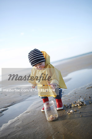 A 1 year old boy plays on the beach