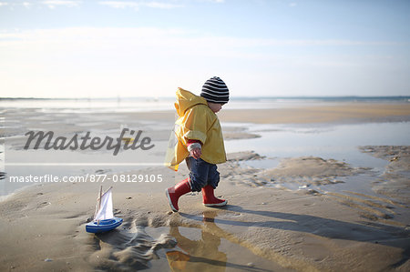 A 1 year old boy plays on the beach