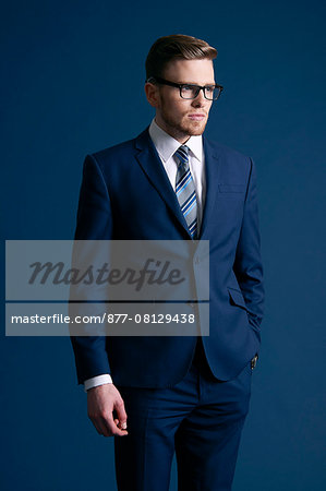 man in blue suit, glasses, blue background, tie, watch