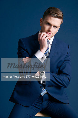 man in blue suit, glasses, blue background, watch