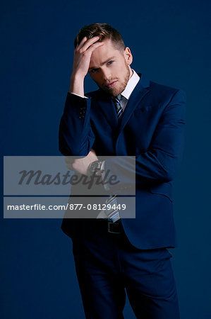 man in blue suit, tie, beard; blue background,watch