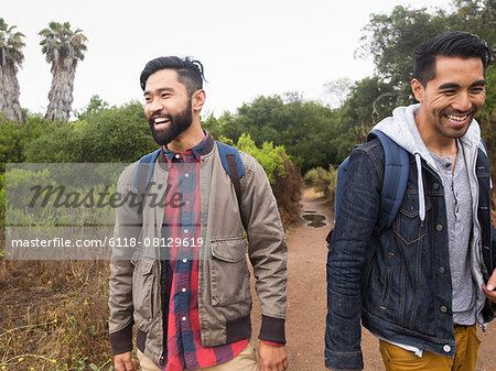 Two smiling young men walking in a park.