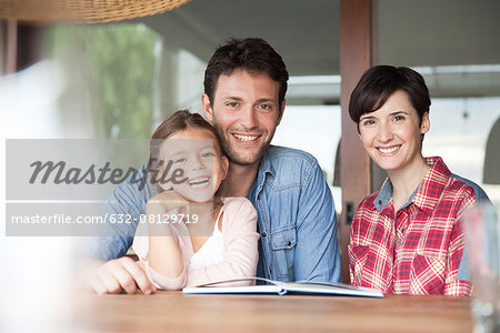 Family sitting together at table with open book, portrait