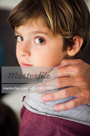 Parent's hand on boy's shoulder, cropped