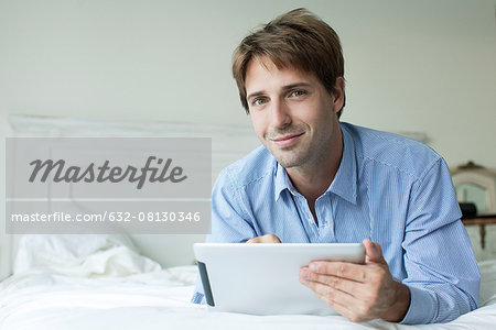 Man lying in bed using digital tablet