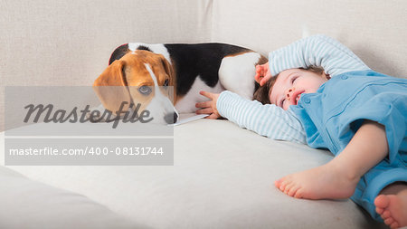 1 year old baby boy playing with his beagle pet dog.