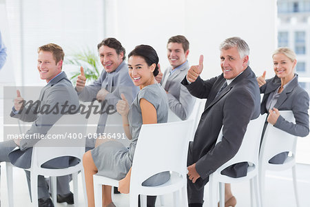 Smiling business team looking at camera during conference in meeting room
